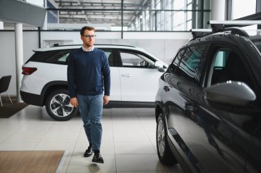 Bugün yeni bir araba aldım. Yerel bayilikte yeni arabasının yanında poz veren mutlu, olgun bir adamın portresi..