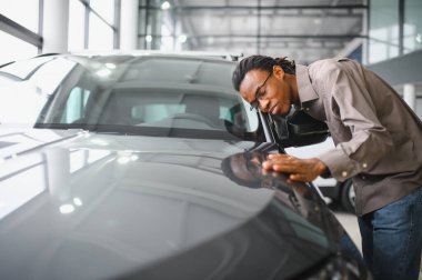Genç Afrikalı Amerikalı adam araba galerisinde yeni bir araç seçiyor..