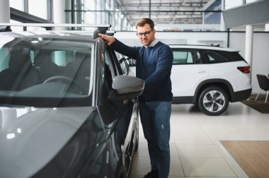 Bugün yeni bir araba aldım. Yerel bayilikte yeni arabasının yanında poz veren mutlu, olgun bir adamın portresi..