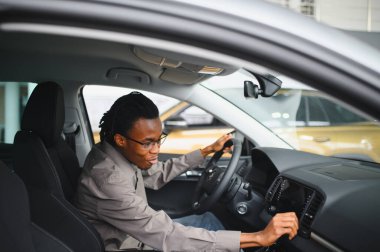 Genç yakışıklı bir adam araba galerisinde araba seçiyor..