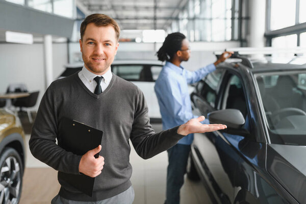 Portrait of Modern car seller standing in car salon with copy space.