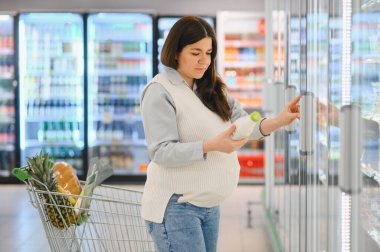Güzel hamile kadın marketten süt alıyor..