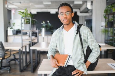 Bir üniversite ortamında odaklanmış bir öğrenci, elinde kitaplar ve bir sırt çantası, akademik adanmışlığı ve tıp alanında gelecekteki başarıyı simgeliyor.