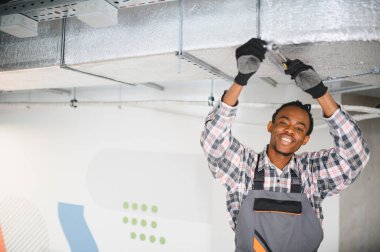 Havalandırma üzerinde çalışan profesyonel teknisyen verimli bir operasyon sağlıyor. Modern bir ortamda bakım ve onarıma odaklan.