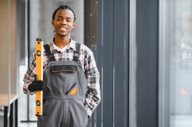 Gülümseyen Afro-Amerikan inşaat işçileri pencere kenarında durup inşaat sektöründe profesyonellik ve uzmanlık gösteriyorlar.