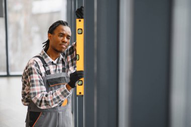 Modern bir bina ortamında düzgün bir hizalama sağlamak için, doğru kurulum için bir seviye kullanarak odaklanmış iş kıyafeti teknisyeni