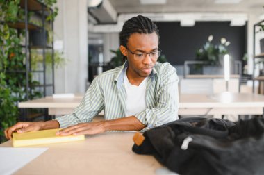 Genç Afrikalı Amerikalı öğrenci üniversite kütüphanesinde okuduktan sonra kitabı kapatıyordu, ayrılmaya hazırlanıyordu.