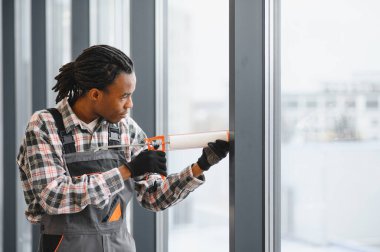 Pencereyi kapatmak için kazıma tabancası kullanan kendini adamış işçiler modern bir binada uygun havalandırma ve havalandırma bakımını sağlıyorlar.