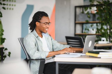 Üniversitede okuyan Afrikalı Amerikalı bir tıp öğrencisi. Etrafı kitaplarla çevrili ve mezuniyete hazırlanan bir dizüstü bilgisayar kullanıyor.