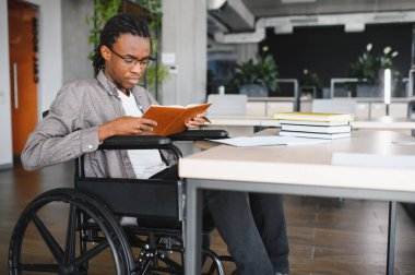 Parlak ve geniş bir kütüphanede okuyan, kendini adamış ve odaklanmış genç bir adam.