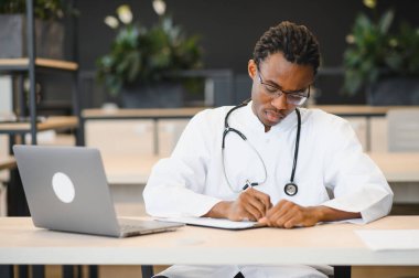 Tıp bürosuna not alan, profesyonellik ve sağlık uzmanlığı sergileyen odaklı pratisyen.