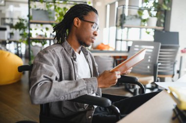 Engelli bir genç, parlak, modern bir ofis alanında öğrenim görüyor, eğitime dahil edilme ve erişilebilirlik gösteriyor