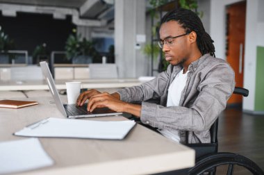 Özürlü genç bir adam dizüstü bilgisayarda çalışıyor, işe dahil olma ve iş yerinde erişilebilirlik gösteriyor