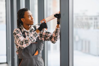 Profesyonel bir işçi pencere çerçevesine dolgu macunu sürüyor, hava geçirmez ve hava geçirmez kurulumunu sağlıyor