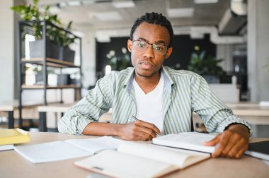 Afrika kökenli Amerikalı bir öğrenci, etrafı kitaplarla çevrili bir üniversite kütüphanesinde özenle okuyor, tıp diplomasıyla mezun olmayı hedefliyor.