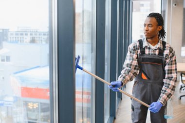 Afrika kökenli Amerikalı işçiler büyük ofis pencerelerini silip, koruyucu eldiven ve tulum giyip, net bir görüş alanı sağlıyor.