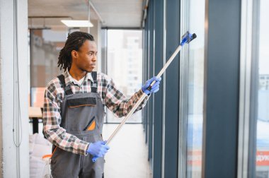 Üniformalı usta işçiler büyük ofis pencerelerini silip modern çalışma alanlarında temiz ve lekesiz cam yüzeyleri sağlıyorlar.