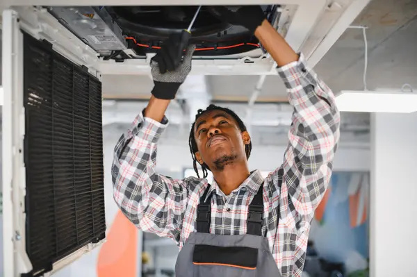 Elektrikçi tornavidayla havalandırma sistemini tamir ediyor. İç mekandaki soğutma ekipmanlarını özenle koruyor.