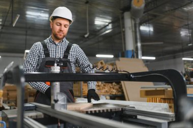 Güvenlik kaskında usta bir marangoz. Cnc makinesi kullanıyor. Mobilya fabrikasında odun kesiyor.