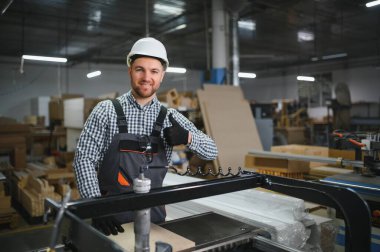 Mobilya fabrikasında cnc makinesi kullanırken, kaliteli işçilik ve iş memnuniyetini gösteren yetenekli bir marangoz.