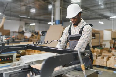 Odaklanmış Afro-Amerikan marangoz modern bir marangoz işletiyor, hassas ve becerikli bir fabrika ortamında mobilya parçaları üretiyor.