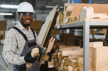 Mobilya fabrikasında ahşap parçaları inceleyen marangoz, üretim sürecinde kalite ve hassasiyet sağlıyor.