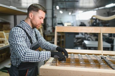 Marangoz mobilya fabrikasında yayları birleştiriyor, işçilik ve üretim sürecine odaklanıyor