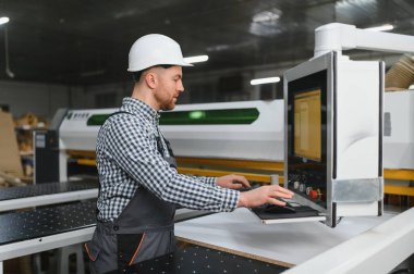 Mobilya fabrikasında çalışan bir işçi. Kanepe imalatı için yüksek kaliteli ahşap bileşenler üretmeye odaklanıyor.