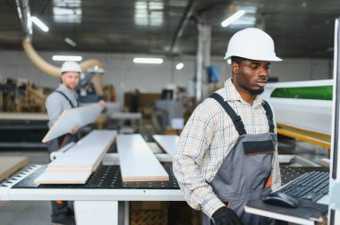 Marangozlar işlek bir kanepe fabrikasında bilgisayar sayısal kontrol makinesinin yanında ahşap paneller üzerinde ustalıkla çalışıyorlar.