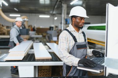 Bir mobilya fabrikasında kanepe üretimi için tahta paneller kesen iki fabrika işçisi.