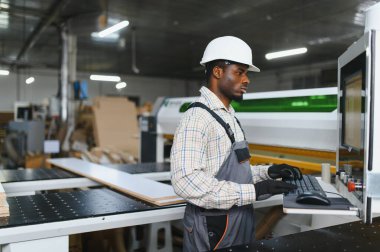 Marangoz, mobilya fabrikasında odun kesmek için bilgisayar sayısal kontrol makinesi kullanıyor.