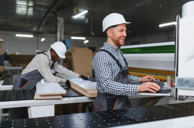 Modern bir ahşap fabrikasında mobilya parçaları üreten iki farklı fabrika işçisi.