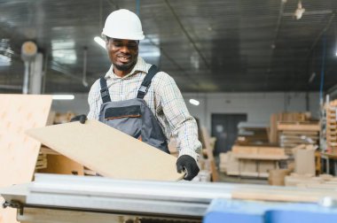 Marangoz bir mobilya fabrikasında ahşap bir paneli idare ediyor, el işi ve endüstriyel üretim yapıyor.