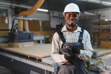 Mobilya fabrikasında cnc makinesini kontrol eden marangoz, modern ahşap işçiliğinde uzmanlığı vurguluyor.