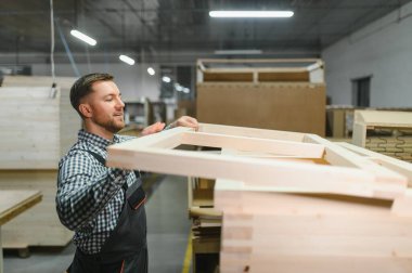 Adanmış işçiler, modern üretim ortamında bir mobilya fabrikasında ahşap bir kanepe çerçevesi, zanaatkarlık ve hassasiyet sergiliyor.