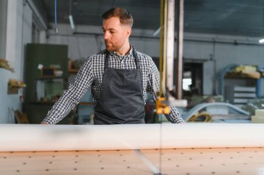 Mobilya fabrikasında çalışan işçiler, kanepe üretimi, işçilik ve teknoloji entegrasyonu için bir cnc makinesi çalıştırmaya odaklanıyor.