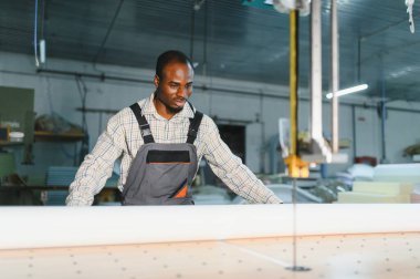 Marangoz bir cnc makinesi çalıştırıyor, hareketli bir mobilya fabrikasında koltuklar için kumaş kesiyor, iş başında marifetli zanaatkarlık sergiliyor.