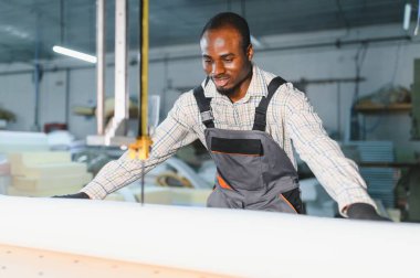 Mobilya üretiminde çok önemli bir adım olan köpüğü kesmek için özel makineler kullanan usta bir zanaatkar.