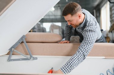 Marangoz mobilya atölyesinde kanepe çerçevesi monte ederek üretim sürecine ve işçiliğe odaklanıyor