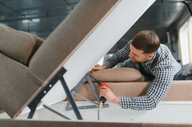 Marangoz bir mobilya fabrikasında kanepe çerçevesi monte etmek için pnömatik bir tornavida kullanıyor.