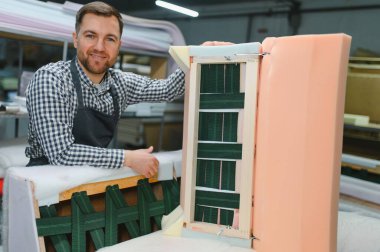 Marangoz mobilya fabrikasında kanepe üretimi için esnek ağlarla ahşap çerçeve monte ediyor.