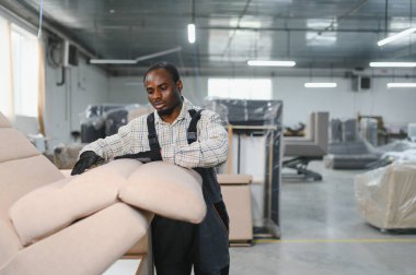 Mobilya imalat tesisinde yüksek kaliteli döşeme ve döşemelerin sağlanması için bir koltukta çalışan yetenekli bir zanaatkar.