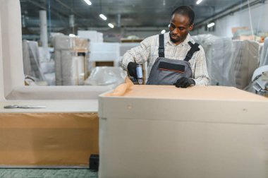 Mobilya fabrikasında çalışan marangoz bir mobilyayı döşemek için pnömatik zımba tabancası kullanıyor.