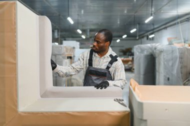 Marangoz, hareketli bir mobilya fabrikasında yüksek kaliteli kumaşla bir kanepeyi ustalıkla döşeyip ustalık ve hassasiyet gösteriyor.