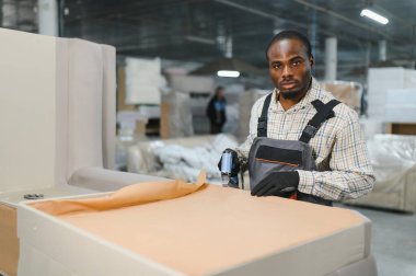 Marangoz, mobilya fabrikasında koltuğu ustalıkla hazırlıyor. Parçayı geliştirmek için ustalıkla döşeme aleti kullanıyor.