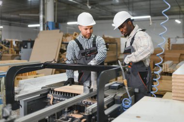 Mobilya üretim tesisinde, mobilya parçaları üreten iki fabrika işçisi