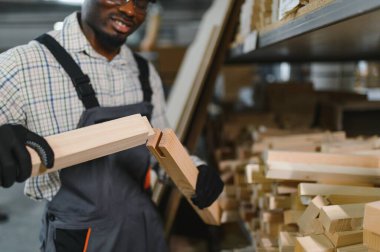 Gülümseyen marangoz hareketli bir mobilya fabrikasında iki ahşap parçayı ustalıkla birleştiriyor, marangozluk ve ahşap işçiliği sergiliyor.