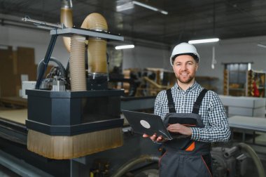 Koltuk üretimi için bir mobilya fabrikasında çalışan bir işçi. Güvenlik teçhizatı ile, süreci bir dizüstü bilgisayarla yönetiyor.