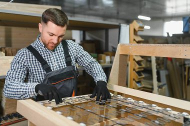 Marangoz ahşap kanepe çerçevesine yayları dikkatlice yerleştiriyor, işçiliğe ve mobilya üretimindeki hassasiyete odaklanıyor