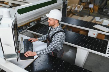 Mobilya fabrikasında çalışan işçiler ahşap kanepe parçaları üretmek için cnc makinesi kullanıyorlar, endüstriyel üretim ve zanaatkarlık sergiliyorlar.